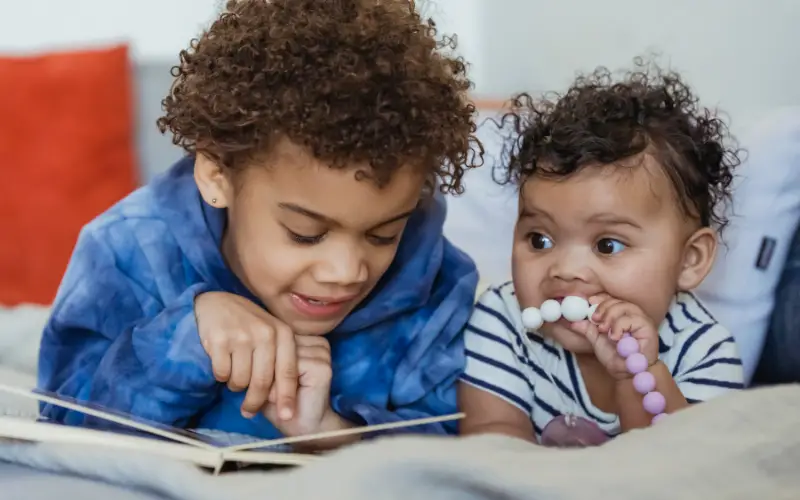 toddler reads to his younger sibling